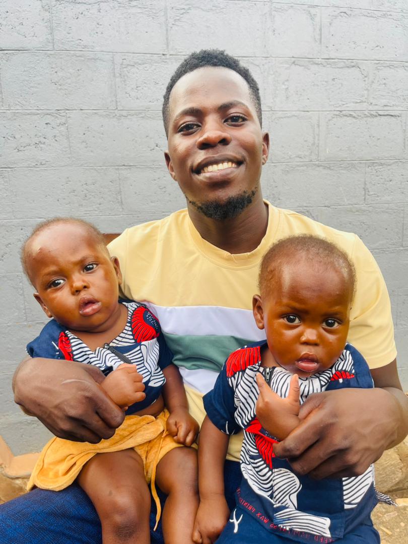 Caretaker holding two young babies cared for by Hope Caring CBO