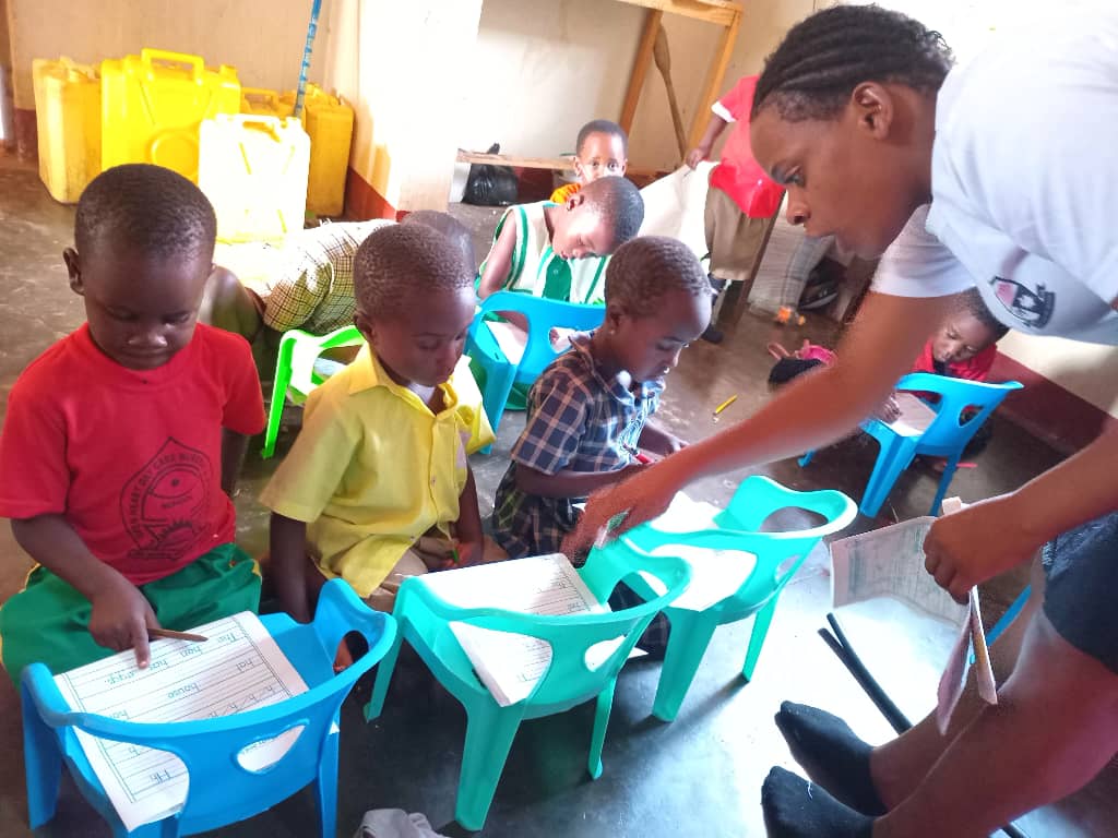 Teacher guiding young students at their desks during a lesson